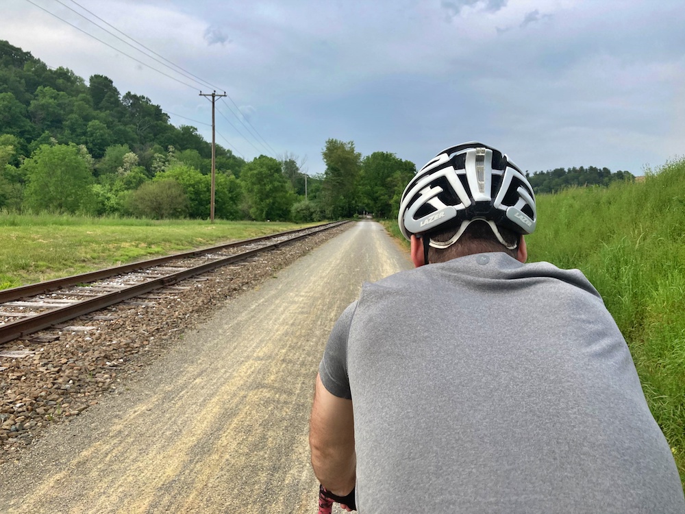 A man bikes next to railroad tracks