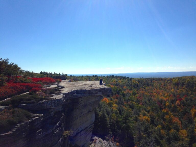 Photo of a person on a rock in fall foliage
